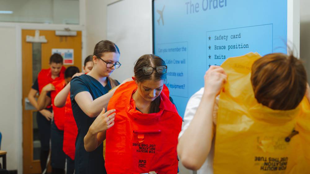 Travel and tourism learners being taught how to wear a life jacket