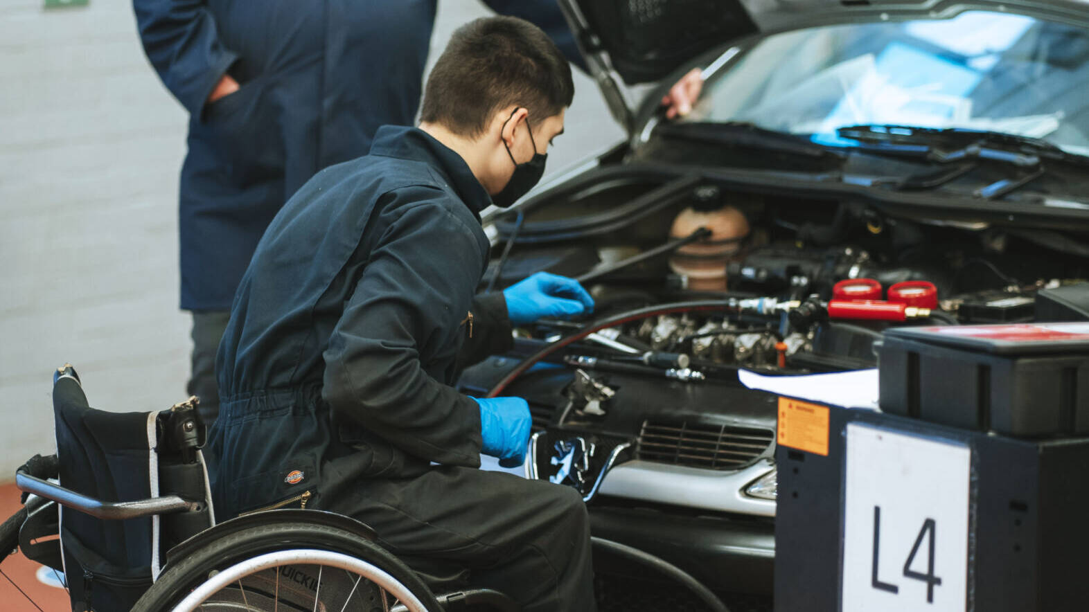 Wheelchaired learner fixing car engine